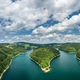 Aggertalsperre Panoramablick auf einen von Wäldern umgebenen, blaugrünen See unter einem bewölkten Himmel.