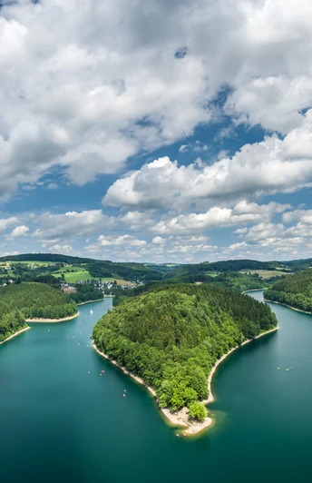 Aggertalsperre Panoramablick auf einen von Wäldern umgebenen, blaugrünen See unter einem bewölkten Himmel.