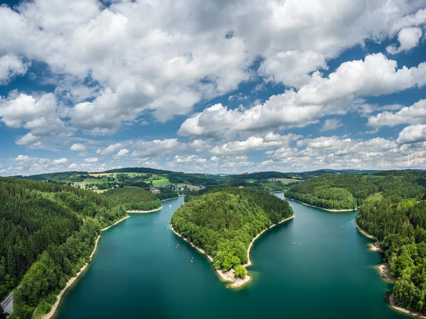 Aggertalsperre Panoramablick auf einen von Wäldern umgebenen, blaugrünen See unter einem bewölkten Himmel.