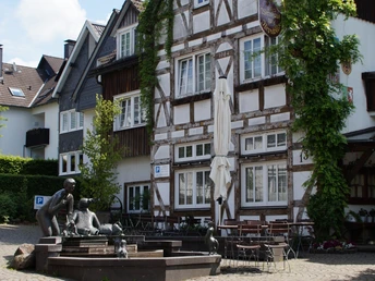 Fachwerkhaus in Morsbach Historisches Fachwerkhaus mit bewachsener Fassade und gemütlichem Straßencafé im Vordergrund.