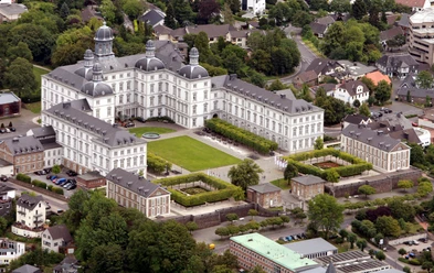 Schloss Bensberg <p>Schloss Bensberg aus der Luft: barockes Gebäude mit symmetrischem Garten, umgeben von grüner Landschaft.</p>