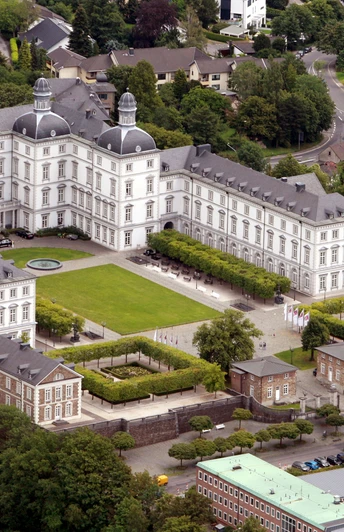 Schloss Bensberg <p>Schloss Bensberg aus der Luft: barockes Gebäude mit symmetrischem Garten, umgeben von grüner Landschaft.</p>