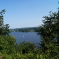 Blick auf den Baldeneysee <p>Blick durch Bäume auf den Baldeneysee in Essen mit Segelboot bei klarem Himmel.</p>