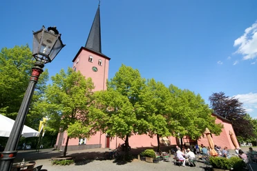 St. Martinus Kirche in Much <p>Historische Kirche in Much: rote Fassade, hoher Turm, sommerlicher blauer Himmel, grüne Bäume.</p>