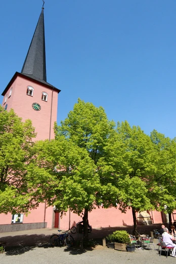 St. Martinus Kirche in Much <p>Historische Kirche in Much: rote Fassade, hoher Turm, sommerlicher blauer Himmel, grüne Bäume.</p>