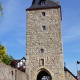 Katharinenturm in Stadt Blankenberg Mittelalterlicher Steinturm mit Torbogen und Fachwerkhaus daneben unter klarem, blauem Himmel.