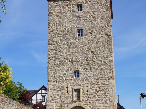 Katharinenturm in Stadt Blankenberg Mittelalterlicher Steinturm mit Torbogen und Fachwerkhaus daneben unter klarem, blauem Himmel.