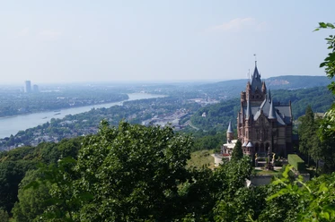 Schloss Drachenburg thront majestätisch über dem Rhein, umgeben von üppigen Wäldern und weiter Landschaft.