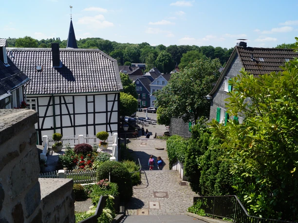 Gräfrather Markt Ein malerisches Fachwerkhaus in einem blühenden Garten, umgeben von Kopfsteinpflasterstraßen.