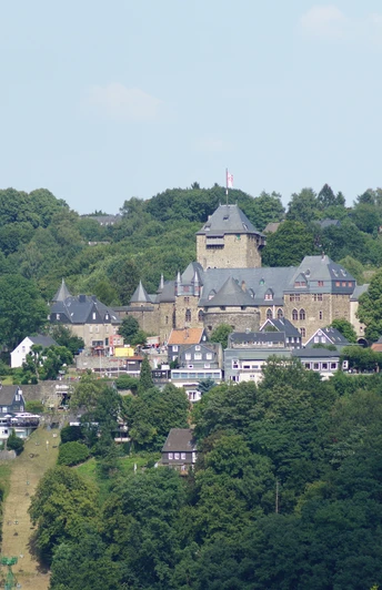 Blick auf Schloss Burg in Solingen, umgeben von grünen Wäldern und traditionellen Fachwerkhäusern.