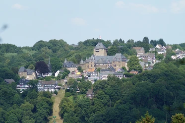 Blick auf Schloss Burg Blick auf Schloss Burg in Solingen, umgeben von grünen Wäldern und traditionellen Fachwerkhäusern.