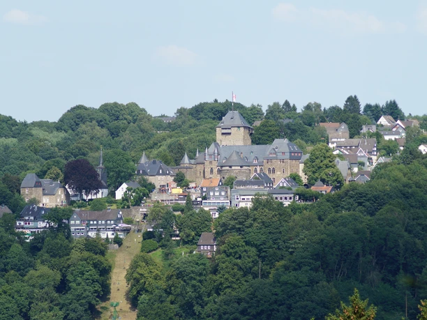 Blick auf Schloss Burg Blick auf Schloss Burg in Solingen, umgeben von grünen Wäldern und traditionellen Fachwerkhäusern.