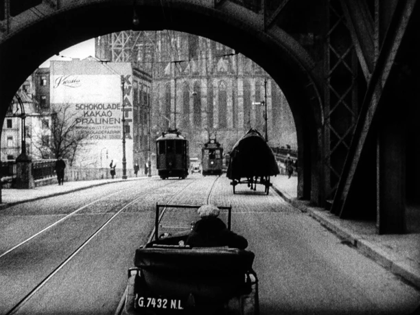 “The Beggar at Cologne Cathedral,” silent film, Germany, 1927 Beggar in a handcart under a bridge, with trams and Cologne Cathedral in the background, 1927