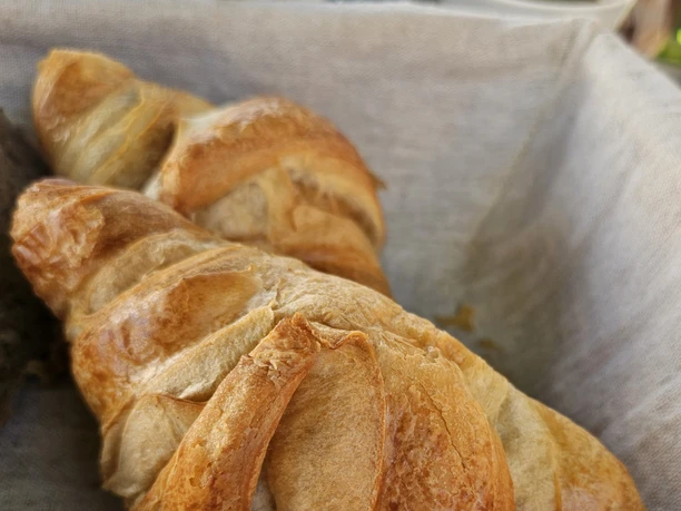 Bistro Lugenstein Frühstück Frische Croissants im Brotkorb mit Kaffee und Kännchen auf der Terrasse.