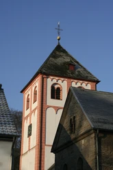 Sankt Pankratius in Odenthal Roter Kirchturm einer romanischen Kirche mit blauen Himmel und Teilen eines angrenzenden Gebäudes.