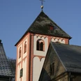 Sankt Pankratius in Odenthal Roter Kirchturm einer romanischen Kirche mit blauen Himmel und Teilen eines angrenzenden Gebäudes.
