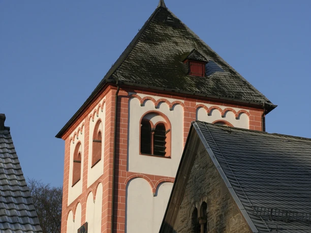 Sankt Pankratius in Odenthal Roter Kirchturm einer romanischen Kirche mit blauen Himmel und Teilen eines angrenzenden Gebäudes.