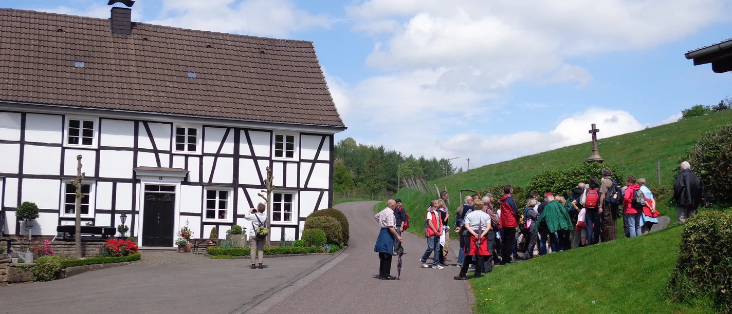 Olpermühle <p>Gruppe von Wanderern vor einem traditionellen Fachwerkhaus in ländlicher Umgebung bei sonnigem Wetter.</p>