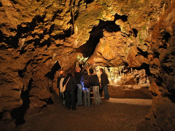 Tropfsteinhöhle in Wiehl Menschen in einer Tropfsteinhöhle, umgeben von stalaktitenbedeckten Wänden.