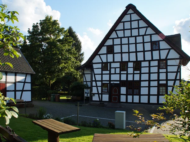 Weißes Pferdchen Fachwerkhäuser mit weiß verputzten Wänden und schwarzen Holzbalken, umgeben von Grünanlagen.