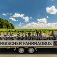 Bus mit Fahrradanhänger Fahrradanhänger voller Fahrräder vor ländlicher Kulisse unter blauem Himmel.