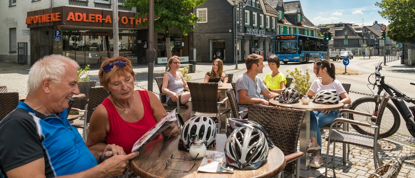 Pause mit dem FahrradBus Personen genießen an einem sonnigen Tag in einem Straßencafé in Wermelskirchen ihre Zeit.