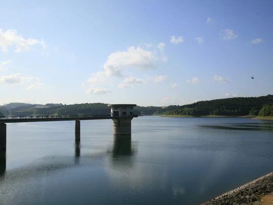Dhünntalsperre im Sommer Ein ruhiges Panorama mit Stausee, einem langen Damm und grünen Hügeln im Hintergrund.