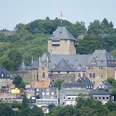 Schloss Burg in Solingen Blick auf eine mittelalterliche Burg mit hohen Türmen, umgeben von üppiger grüner Vegetation.