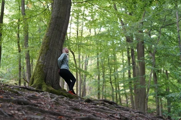 Wanderin im Nationalpark Kellerwald-Edersee am Baumstamm stehend