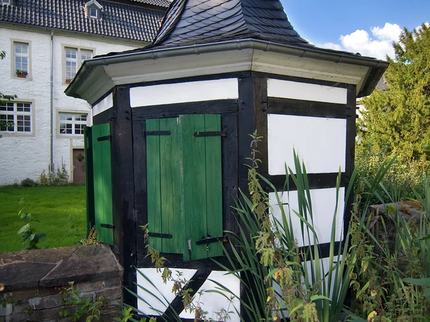 Prozessionswanderweg Denklingen Ein schmuckes Fachwerkhäuschen mit grünem Tor, eingebettet in eine malerische, grüne Gartenlandschaft.