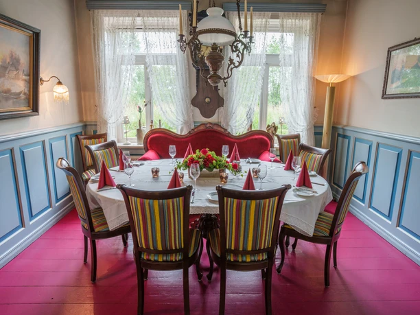 ostfriesenstube.jpg Gedeckter Tisch in historischer Ostfriesenstube mit roten Dielen und blauem Wandpaneel.