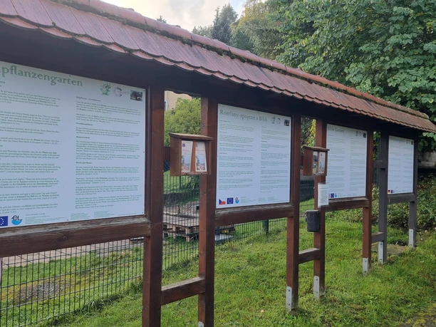 Hinweisschilder Bibelpflanzgarten Informationstafeln in einem Park, mit Texten über Pflanzen und Natur. Grüne Umgebung im Hintergrund.