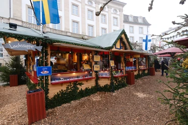 Finnenstand | Märchenweihnachtsmarkt Kassel Links hängt an der Holzhütte ein Schild mit "Lachssuppe". Die Hütte ist aus Holz und weihnachtlich geschmückt.