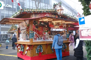 Santas Churros | Märchenweihnachtsmarkt Kassel Eine weihnachtlich geschmückte Holzhütte ist abgebildet.