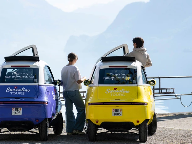 swissolino-brienzersee.jpg Zwei Swissolino-Kleinautos am Brienzersee mit Personen vor Bergkulisse