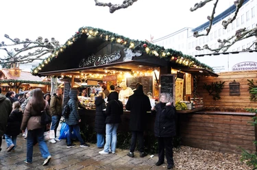 Gabis Creperie | Märchenweihnachtsmarkt Kassel Eine weihnachtlich verzierte Holzhütte mit mehreren Personen befindet sich im Bild.