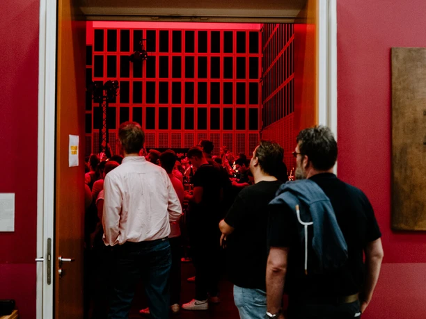 Kölner Museumsnacht 2026 Besucher betreten bei rotem Licht einen Ausstellungsraum der Kölner Museumsnacht