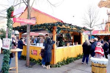 Grill Hütte | Märchenweihnachtsmarkt Kassel Eine geschmückte Holzhütte ist sichtbar. Im inneren der Hütte werden die Speisen zubereitet.