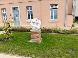 Skulptur Zuflucht Grafenschloss Hoya (2).jpeg Weiße Skulptur „Zuflucht“ auf Ziegelsockel vor dem Grafenschloss Hoya.