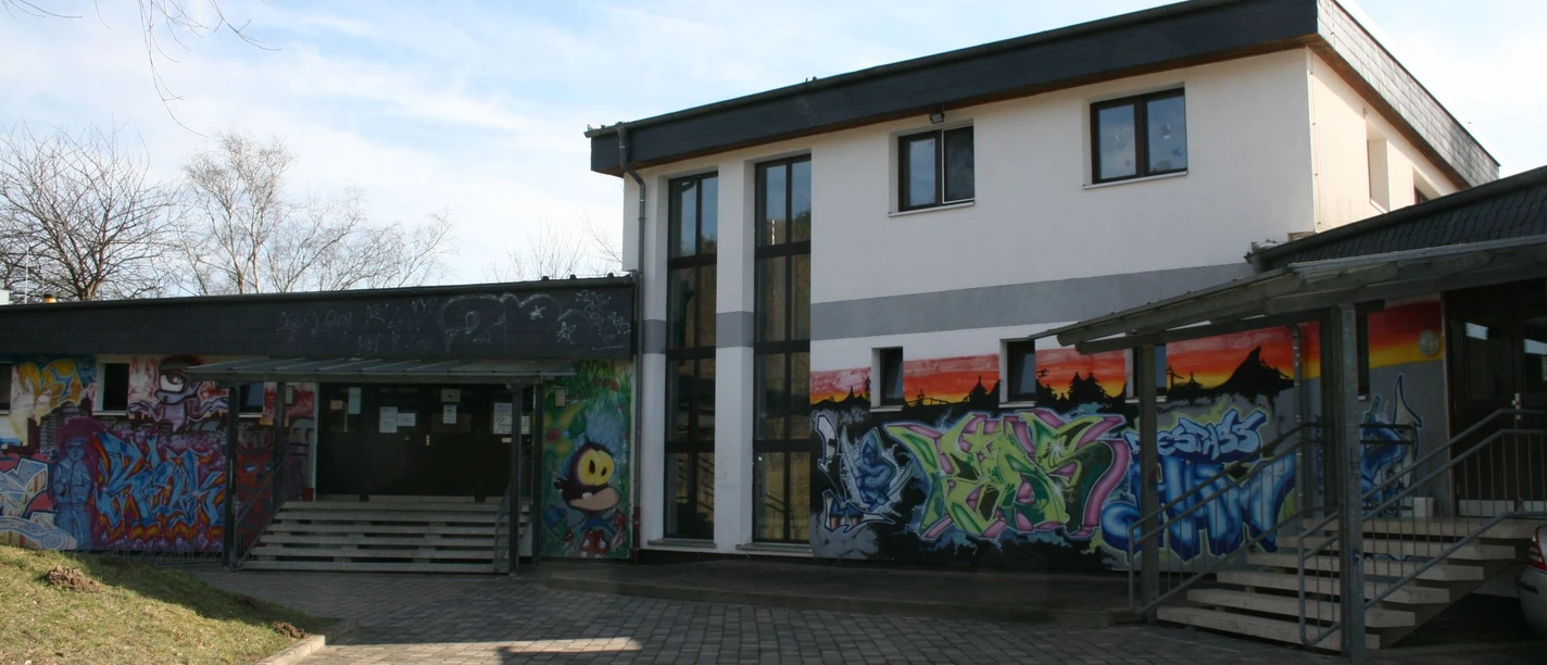 Kinder- und Jugendtreff Hamberg_HD_16zu9.jpg Kinder- und Jugendtreff Hamberg mit Graffiti-Fassade und gepflastertem Vorplatz.