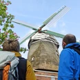 Wanderer schauen auf zu den Flügeln der Windmühle "Henriette" Wanderer schauen auf zu den Flügeln der Windmühle "Henriette" Hikers look up to the wings of the "Henriette" windmillVandrere kigger op på vingerne af "Henriette"-vindmøllenWandelaars kijken omhoog naar de wieken van de windmolen "Henriette