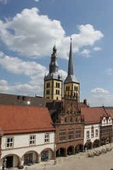 Historisches Rathaus mit prächtigen Türmen und detaillierten Fassaden unter blauem Himmel.