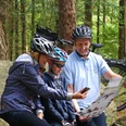 Radler am Steingräberfeld Giersfeld in Ankum Familie mit Fahrradhelmen beim Kartenlesen auf einem Felsen im Wald.