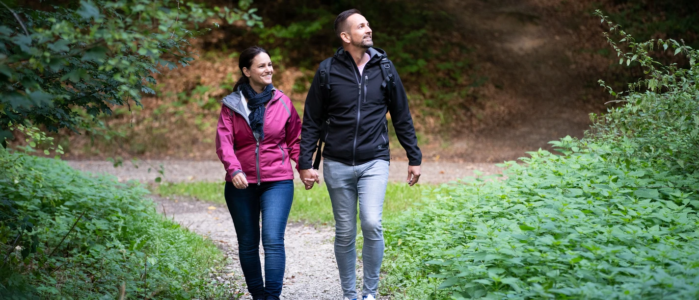 Wandern im Teutoburger Wald Ein paar genießt einen Spaziergang auf einem Waldweg, umgeben von üppigem Grün.