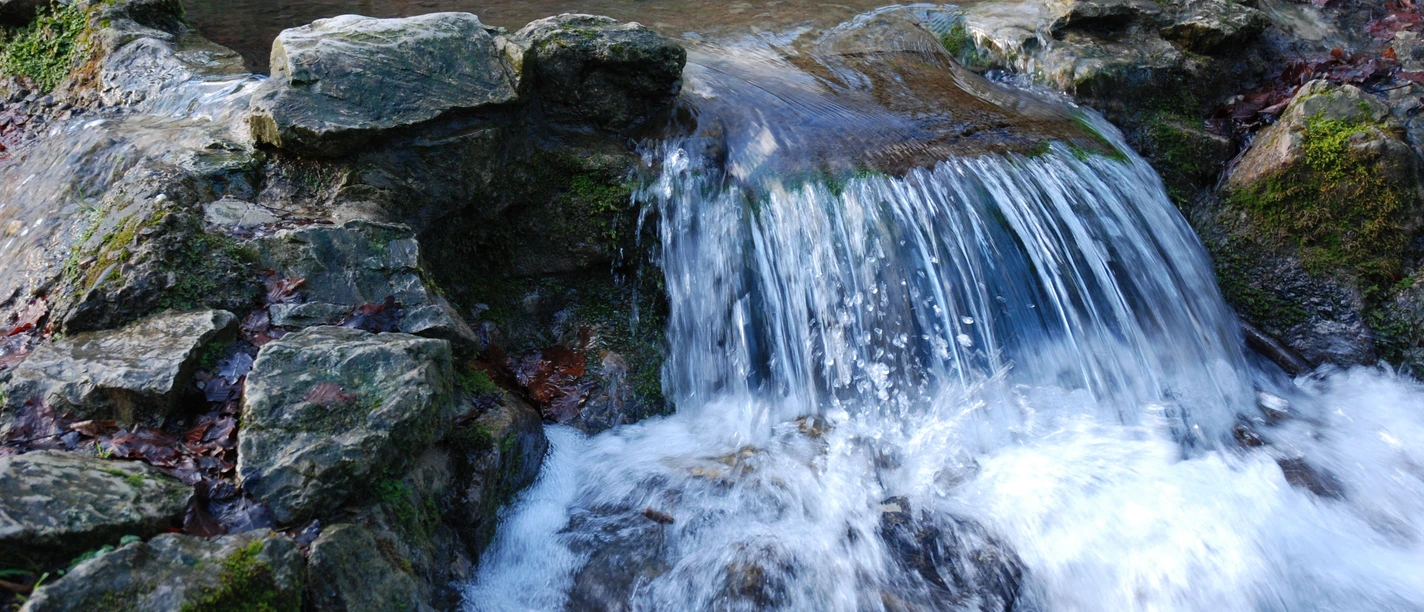 kalksinterterrassen-in-dissen-a-t-w-foto-natur-und-geopark-terra-vita Kleine waterval stroomt over rotsen in een rustige vijver.
