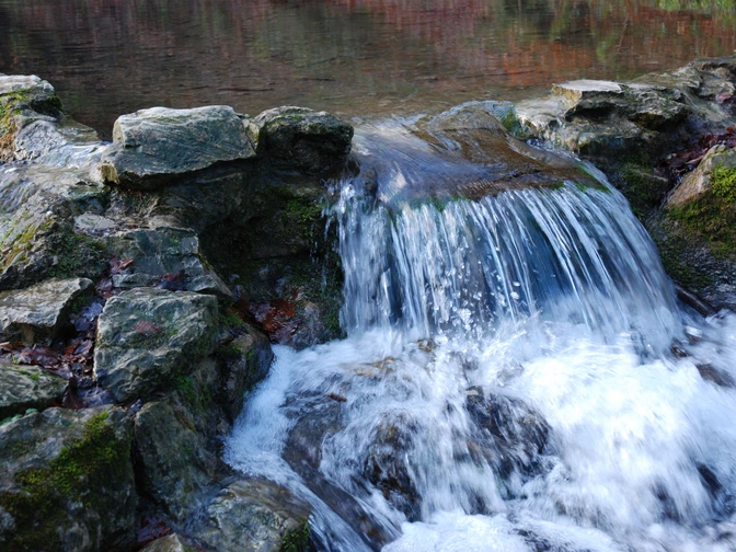 kalksinterterrassen-in-dissen-a-t-w-foto-natur-und-geopark-terra-vita Kleiner Wasserfall fließt über Felsen in einen ruhigen Teich.