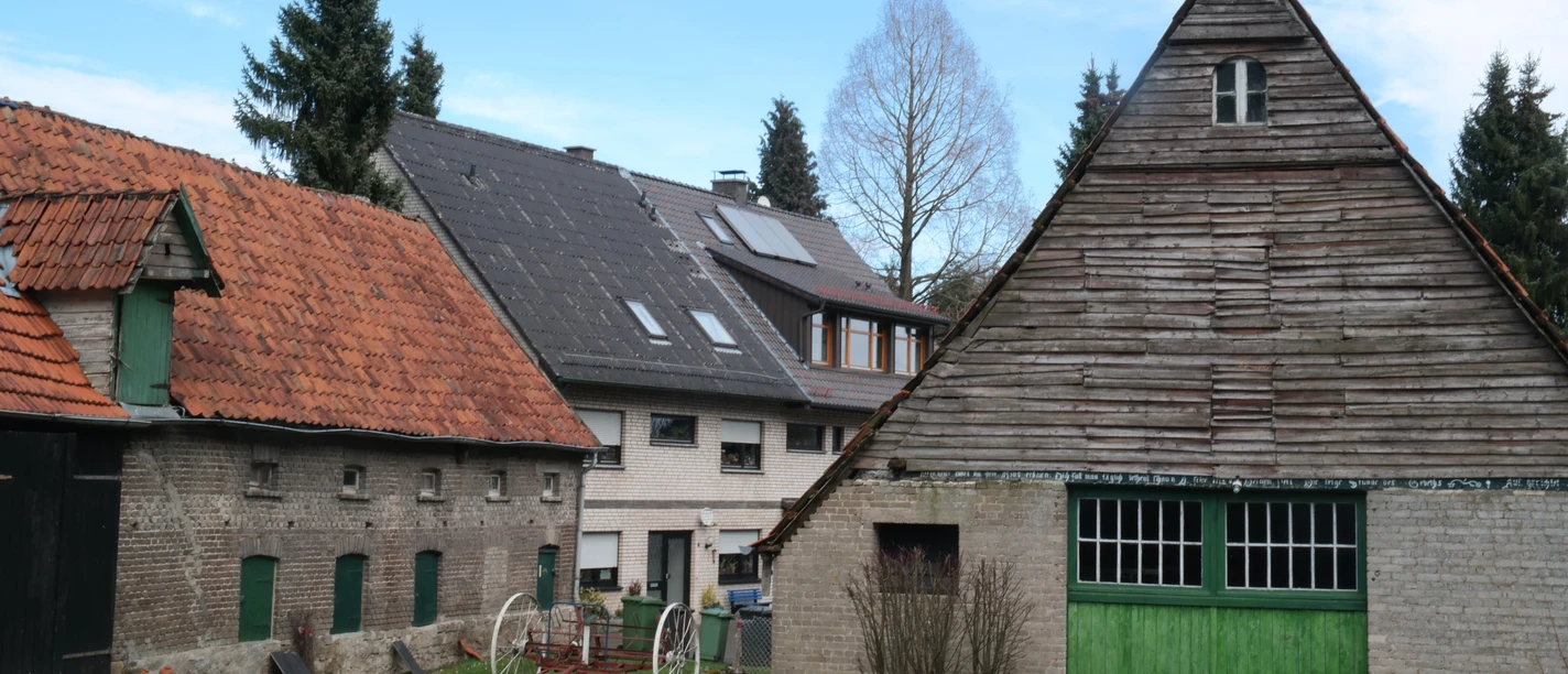Unterwegs auf dem TERRA.track Zittertal Historic farmhouses with distinctive wooden roofs and green doors set against a picturesque backdrop.