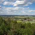 Landschaft von Wäldern und Feldern in sanften Hügeln unter blauem Himmel mit weißen Wolken.Landscape of forests and fields in rolling hills under a blue sky with white clouds.Landskab med skove og marker i bølgende bakker under en blå himmel med hvide skyer.Landschap van bossen en velden in glooiende heuvels onder een blauwe lucht met witte wolken.