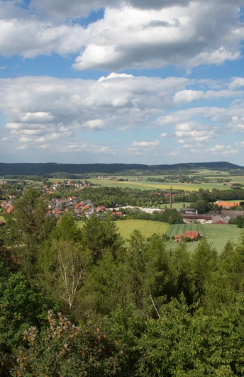 Weitblicke Landschaft von Wäldern und Feldern in sanften Hügeln unter blauem Himmel mit weißen Wolken.Landscape of forests and fields in rolling hills under a blue sky with white clouds.Landskab med skove og marker i bølgende bakker under en blå himmel med hvide skyer.Landschap van bossen en velden in glooiende heuvels onder een blauwe lucht met witte wolken.