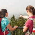 Blick auf Bad Iburg Zwei Wanderer mit Rucksäcken betrachten einen Aussichtspunkt im Wald.Two hikers with rucksacks look at a viewpoint in the forest.To vandrere med rygsække kigger på et udsigtspunkt i skoven.Twee wandelaars met rugzakken kijken naar een uitkijkpunt in het bos.